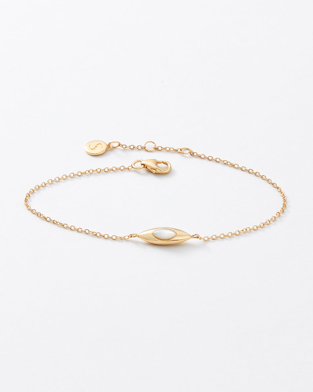 A delicate gold chain bracelet featuring a central oval bezel-set white pearl and a small round engraved tag, displayed on a clean white background.