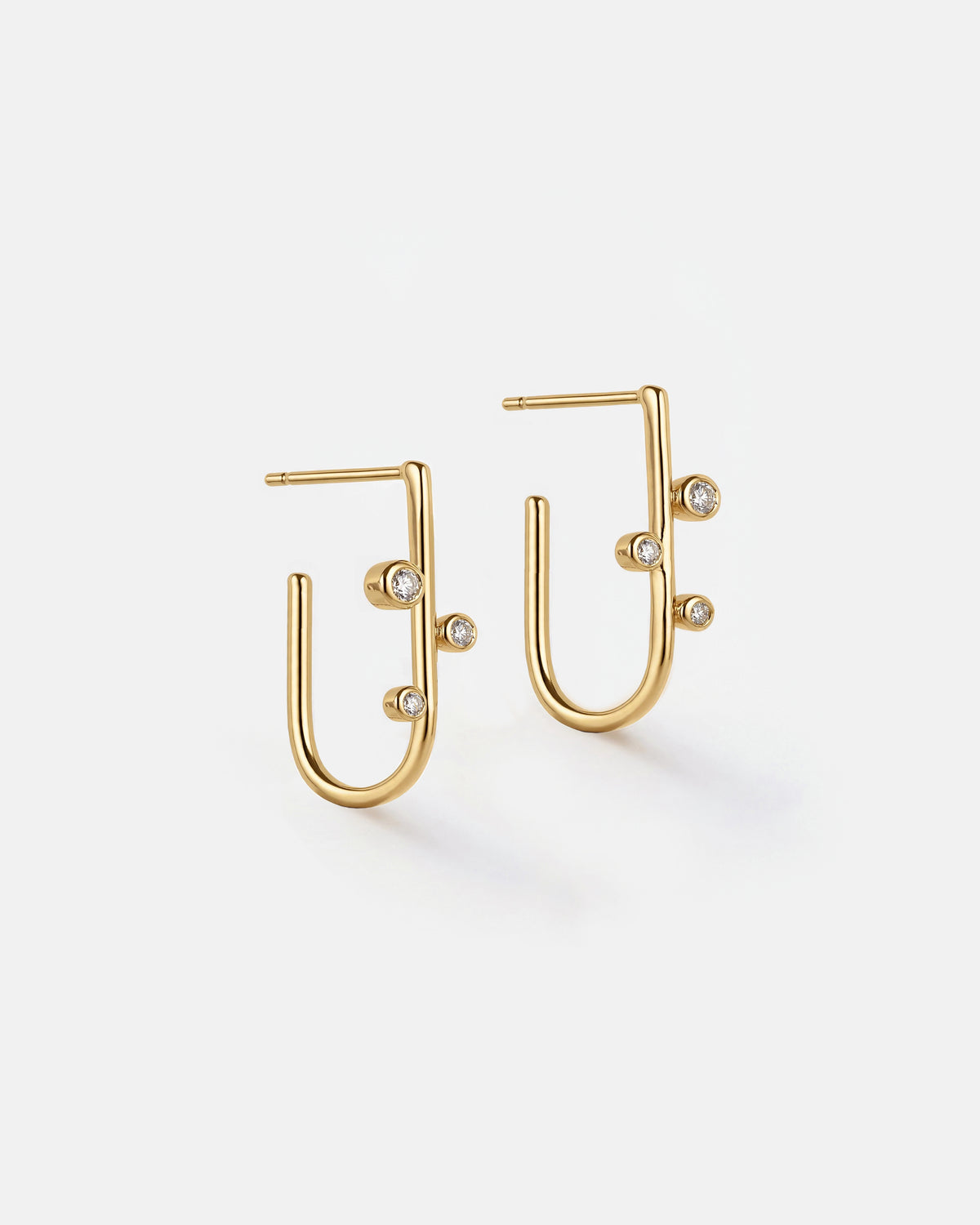 A pair of gold geometric hoop earrings with small clear white topaz accents, displayed on a clean white background.