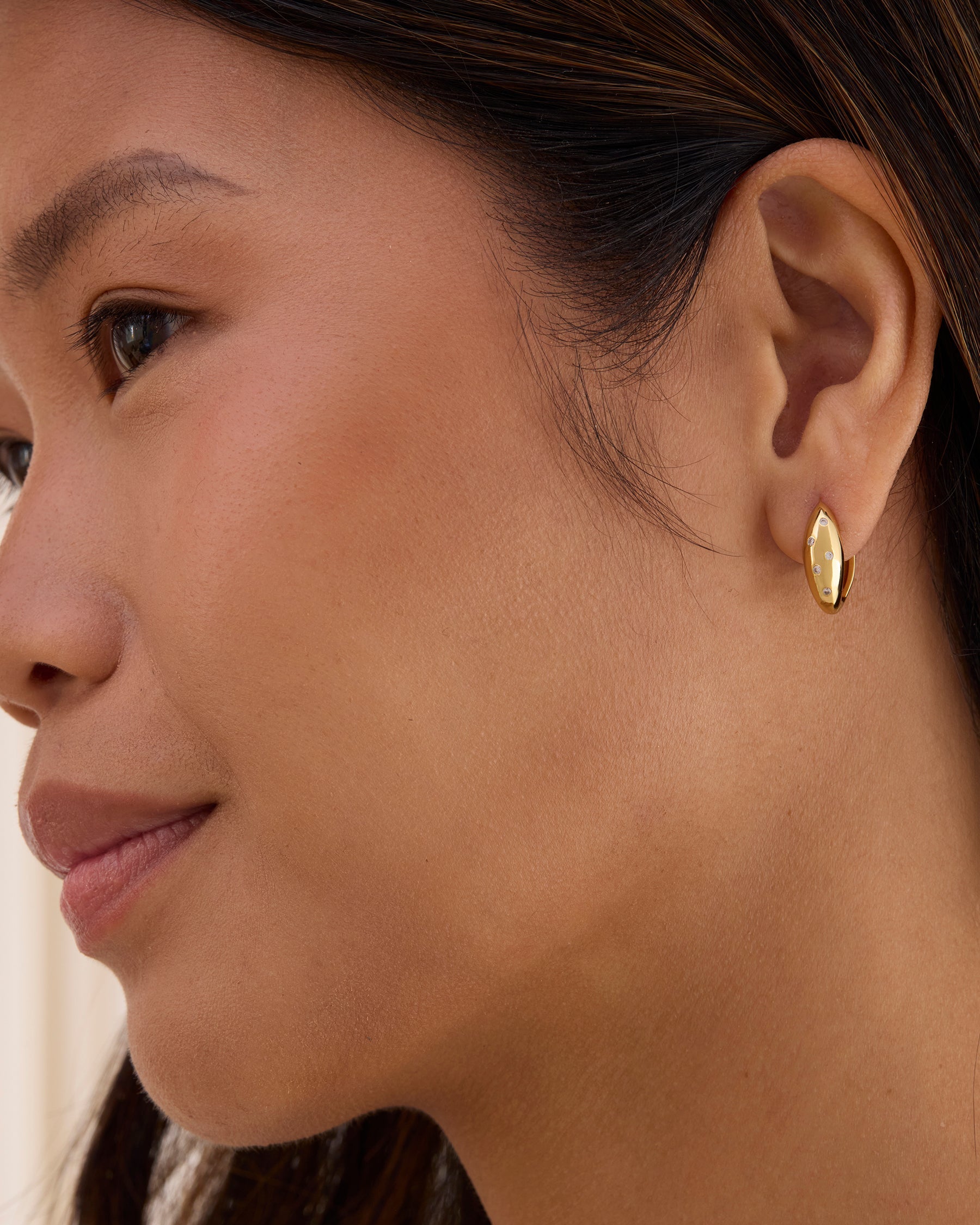 Gold huggie hoops with white sparkling gemstones