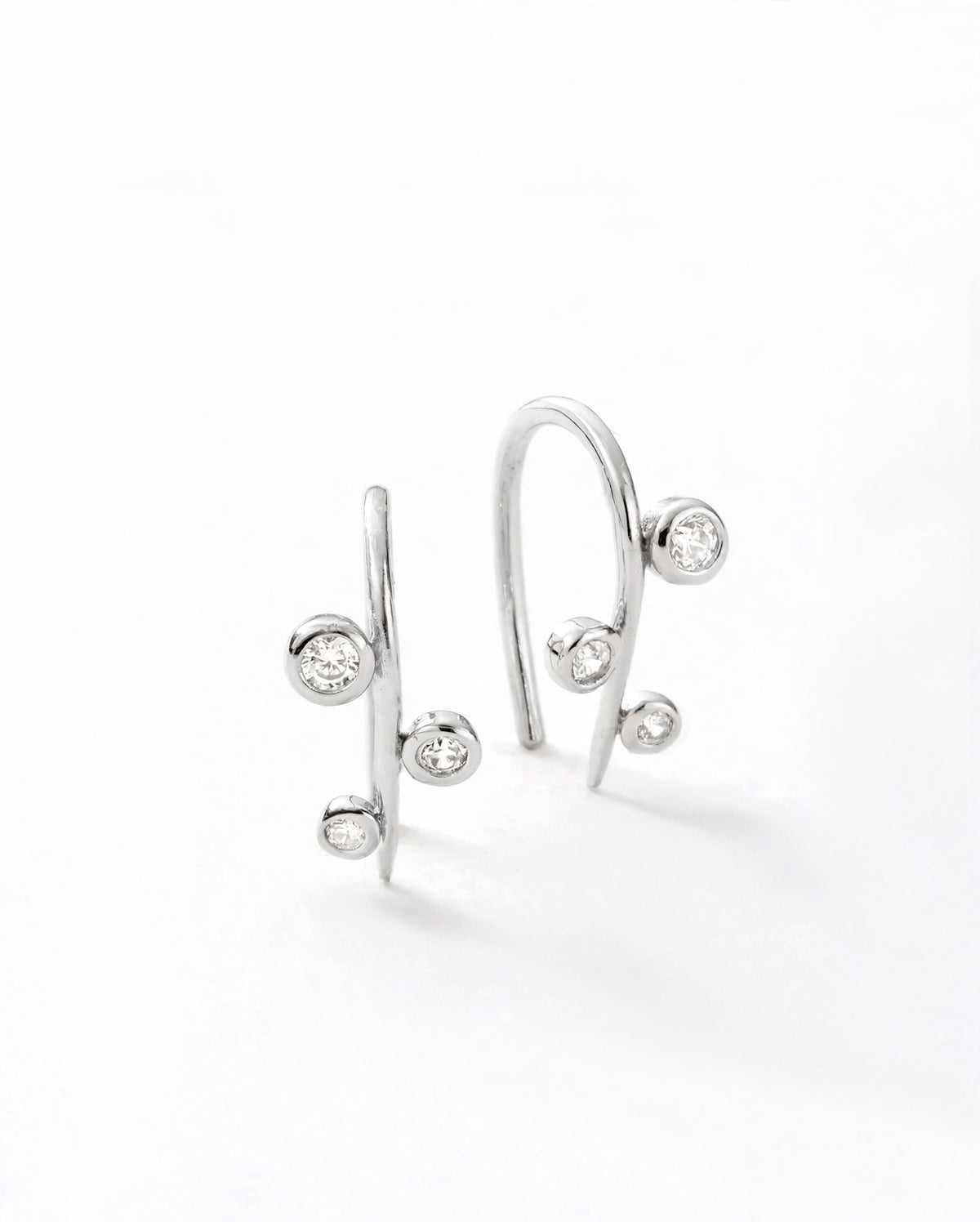 Aralia Tiny Hug earrings in sterling silver with three round bezel-set white cubic zirconia stones along a slender wire