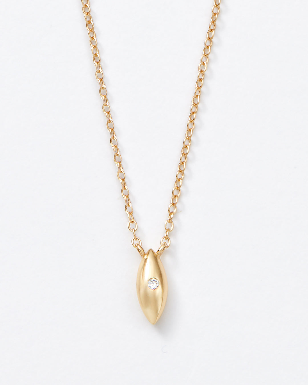 A delicate gold chain necklace featuring a small, polished gold teardrop-shaped pendant with a tiny clear gemstone inset, shown against a plain white background.