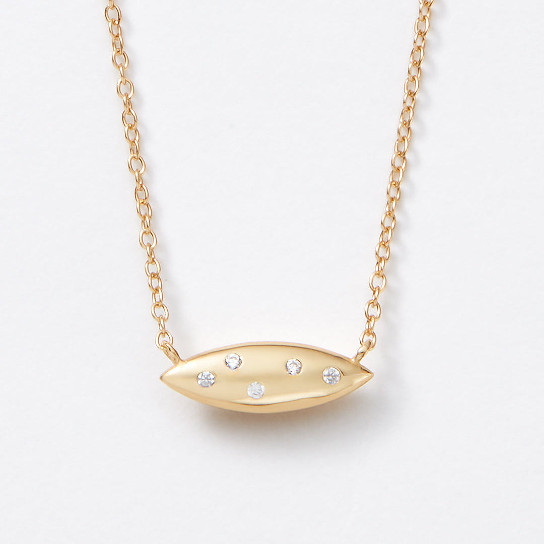 Reversible gold necklace with a unique petal shaped pendant. Mother of pearl and white topaz.