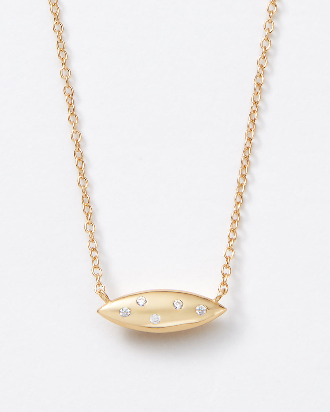 A gold chain necklace with a horizontal bar pendant adorned with small clear topaz gemstones, shown against a plain white background.