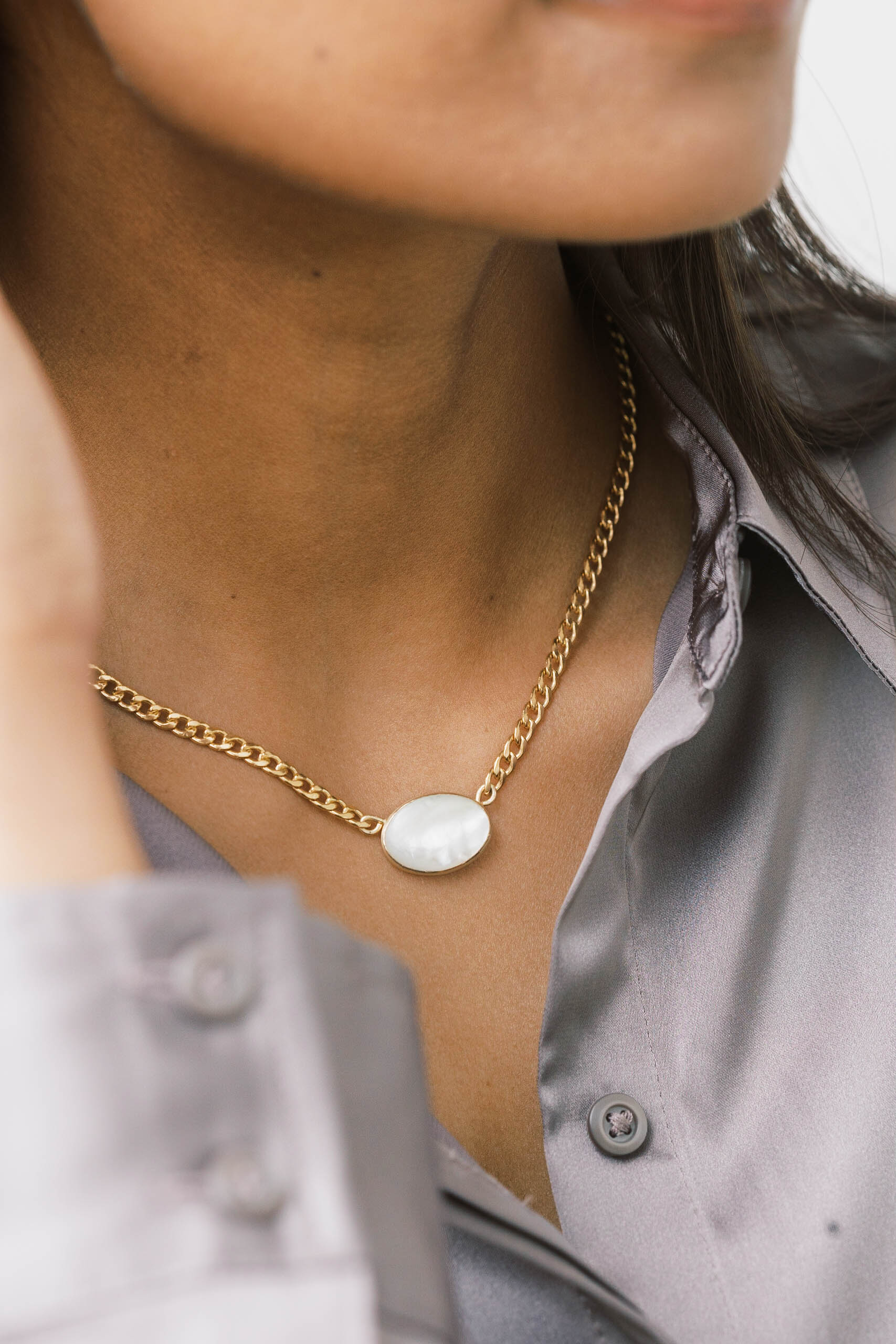 Modern and minimal, oval pearl pendant lays east west on a gold filled curb chain.