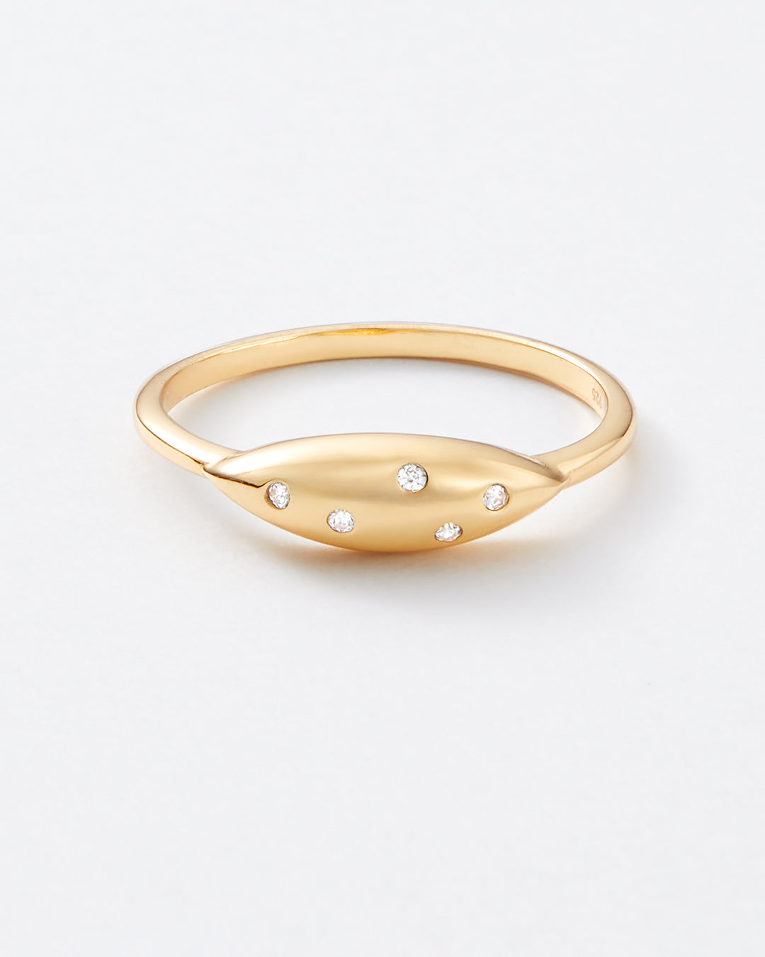 A gold oval ring with five small clear gemstones set along the front, photographed on a clean white background.