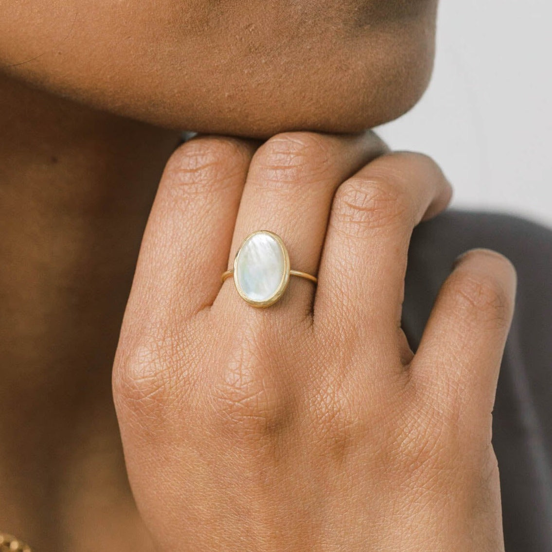 Oval pearl cabochon is set on a gold band. The ring style is minimal modern and timeless.
