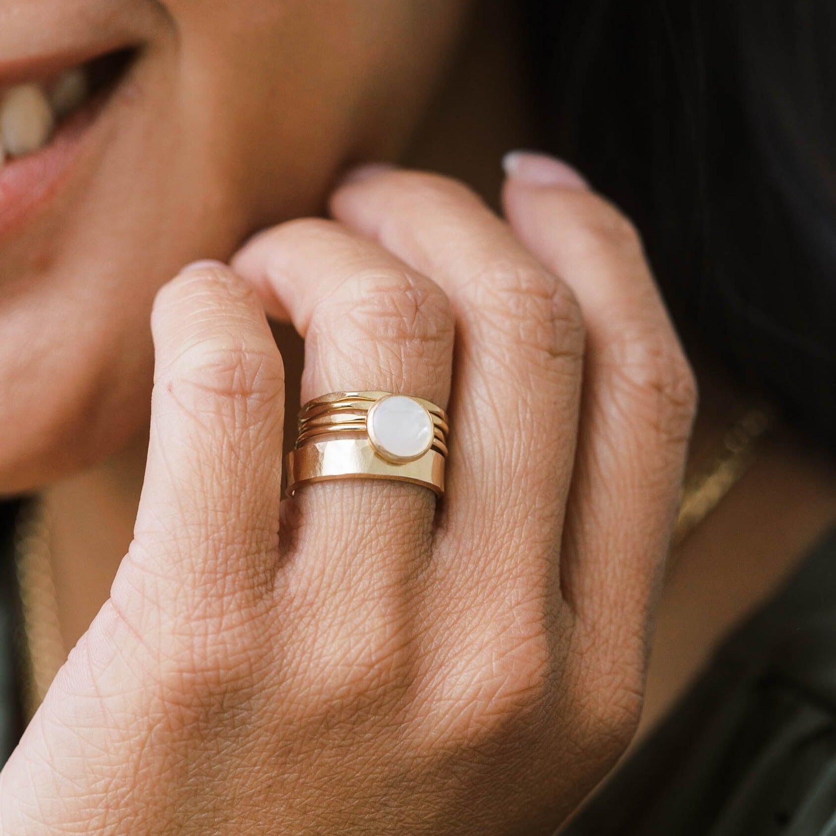 Round gold pearl ring stacked with hammered gold bands and a wide gold band.