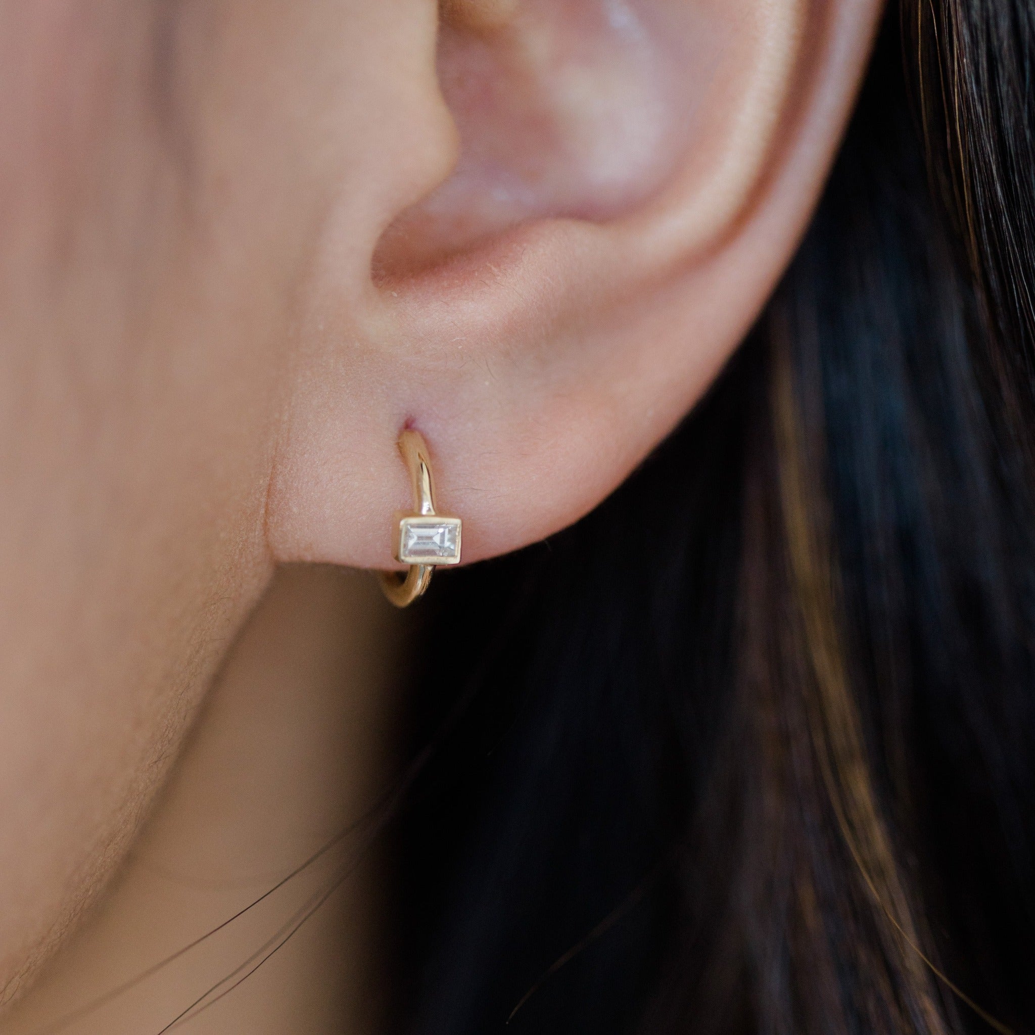 Small dainty gold hoop features one rectangular diamond. It is a minimal design, perfect for a family heirloom.