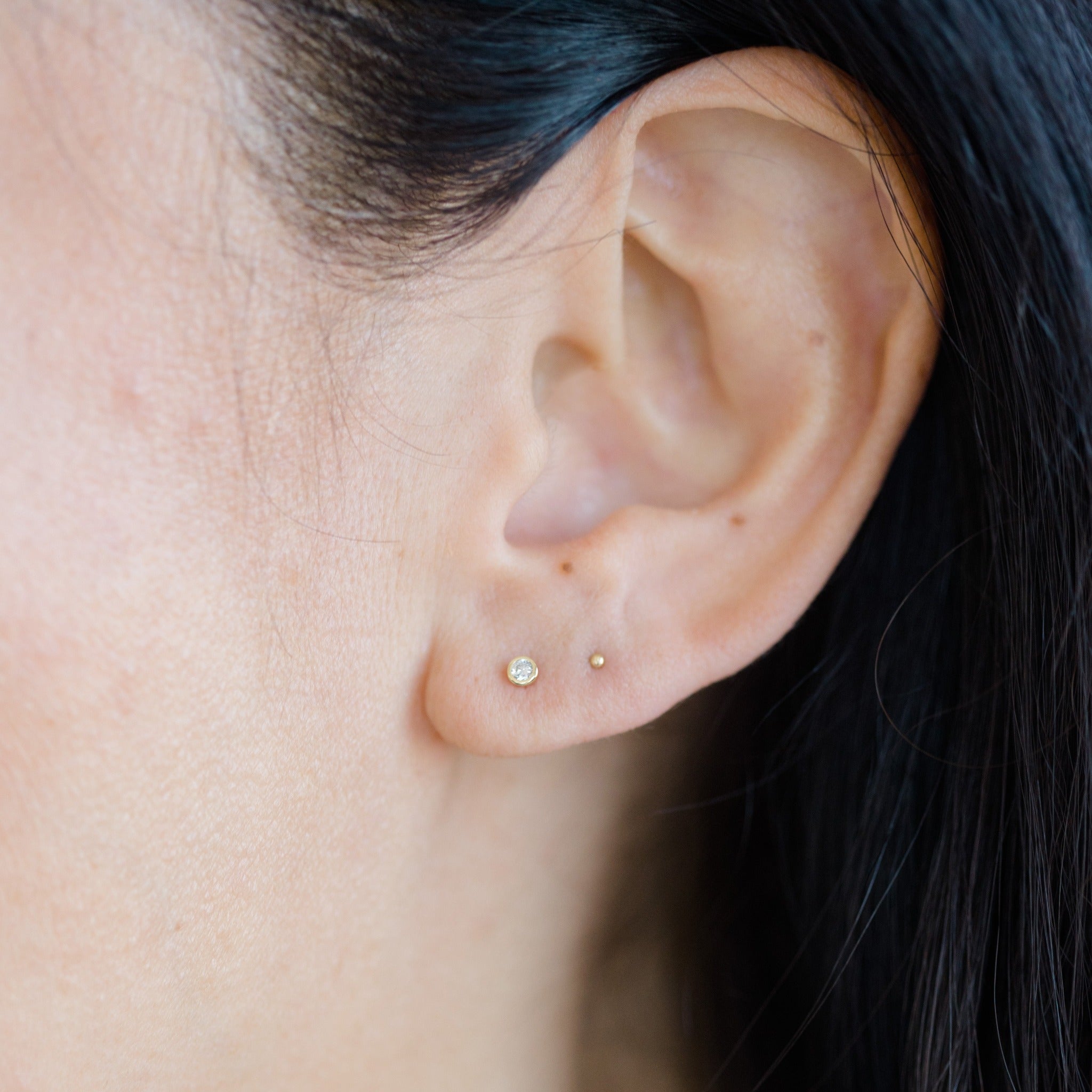 This shiny diamond earring can be combined with other gold stud earrings for a curated earring look.