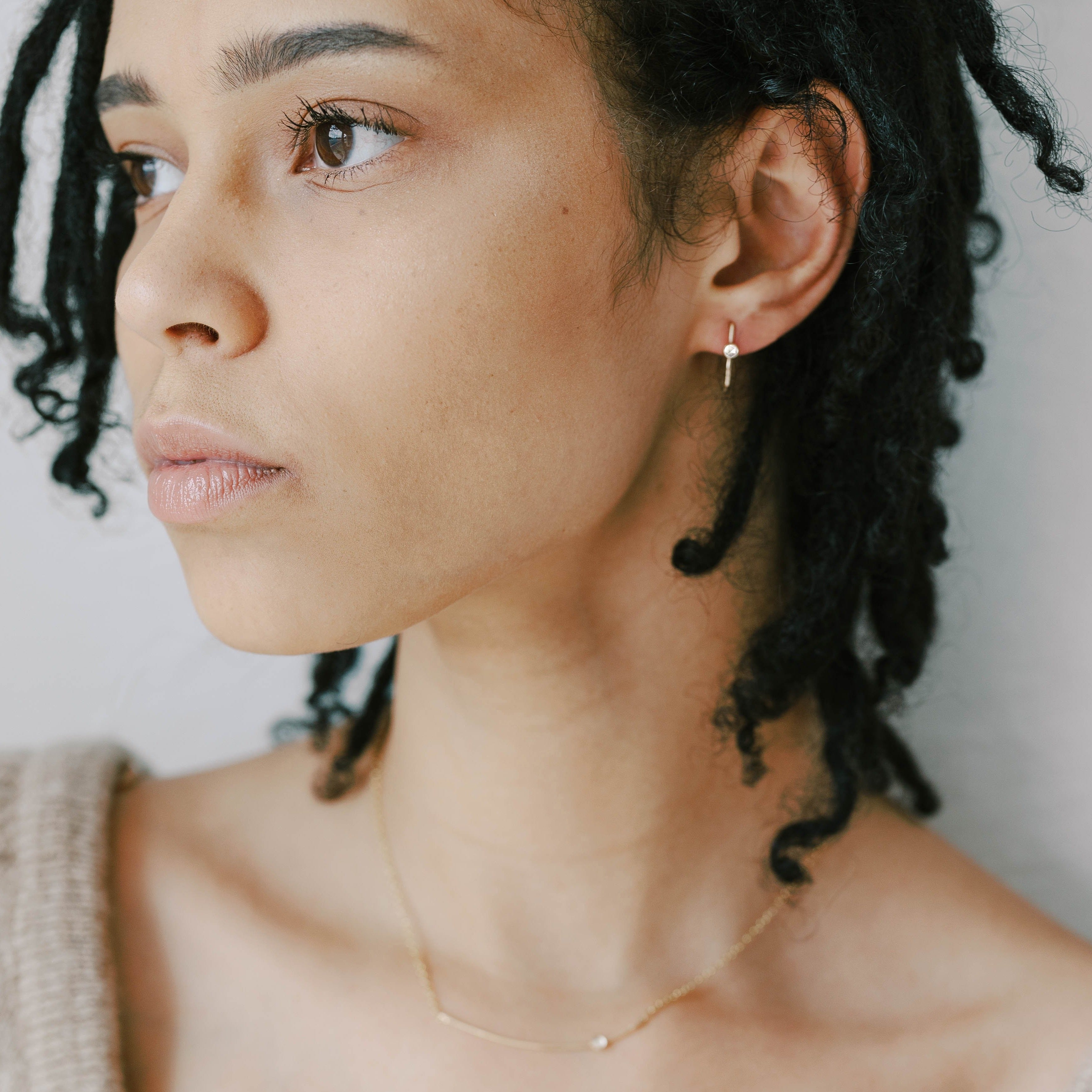 Modern tiny gold hoops made from recycled gold. Small white topaz stones.