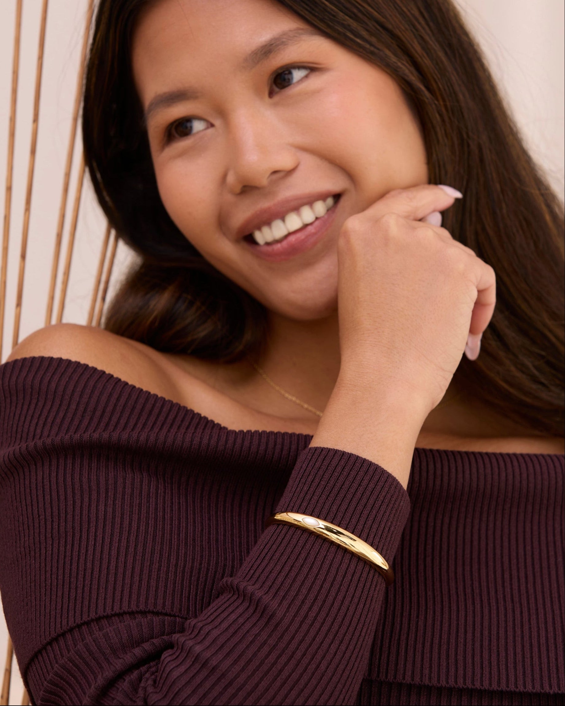 Women with a gold cuff bracelet with a pearl.