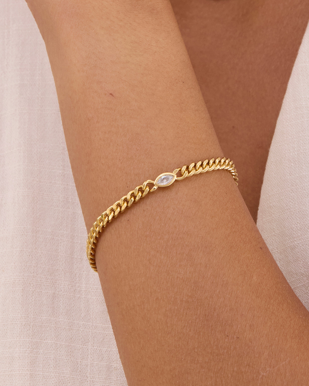 Gold curb chain bracelet with bezel set white gemstone