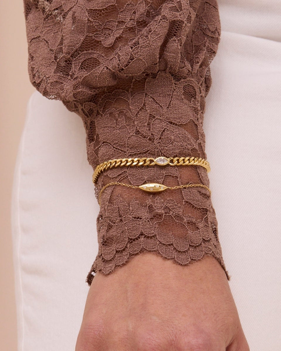 Gold curb chain bracelet with white gemstone and a thin gold chain bracelet with puffy petal shape.