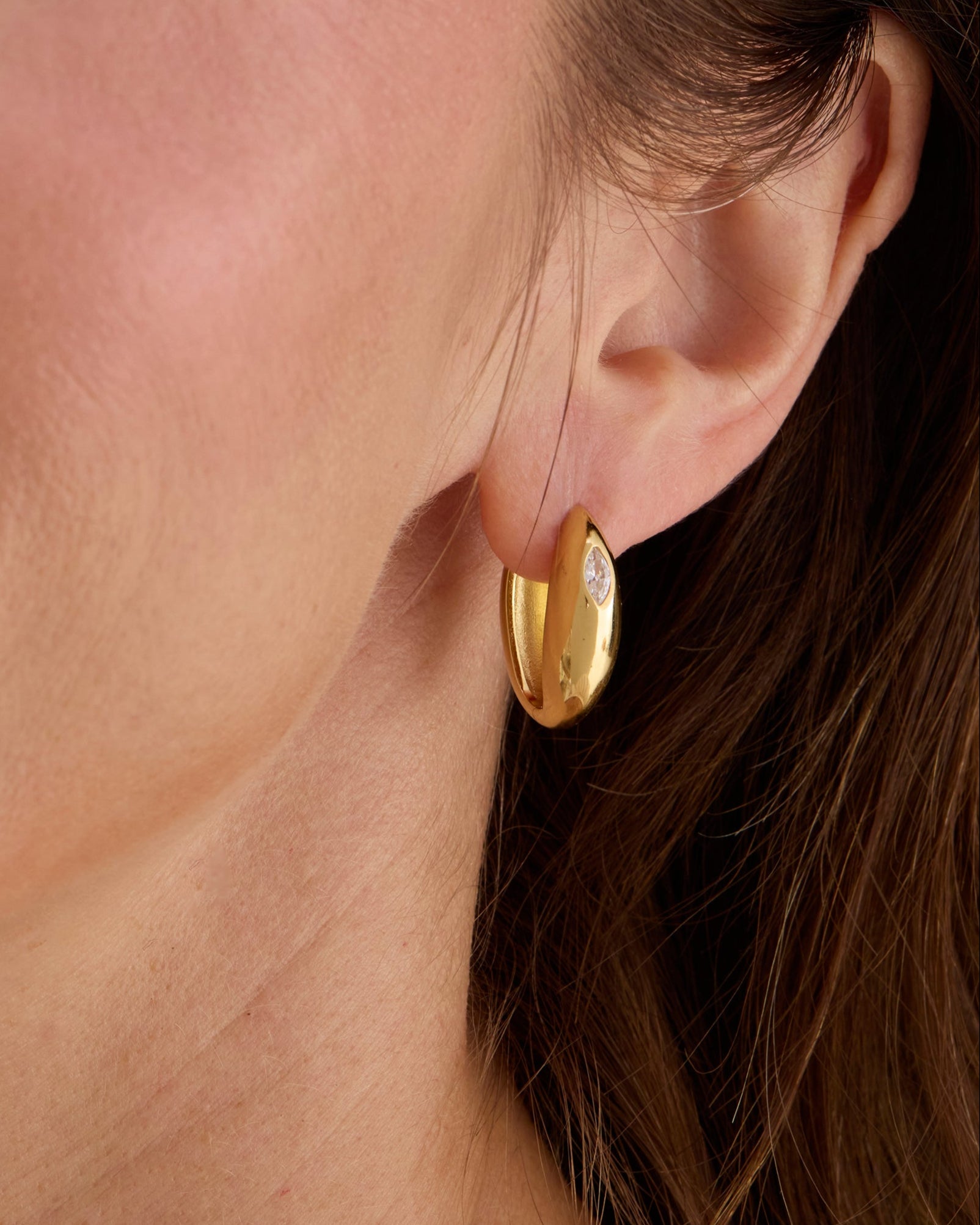 Gold hinge closing hoop earrings with a white gemstone marquise shape.