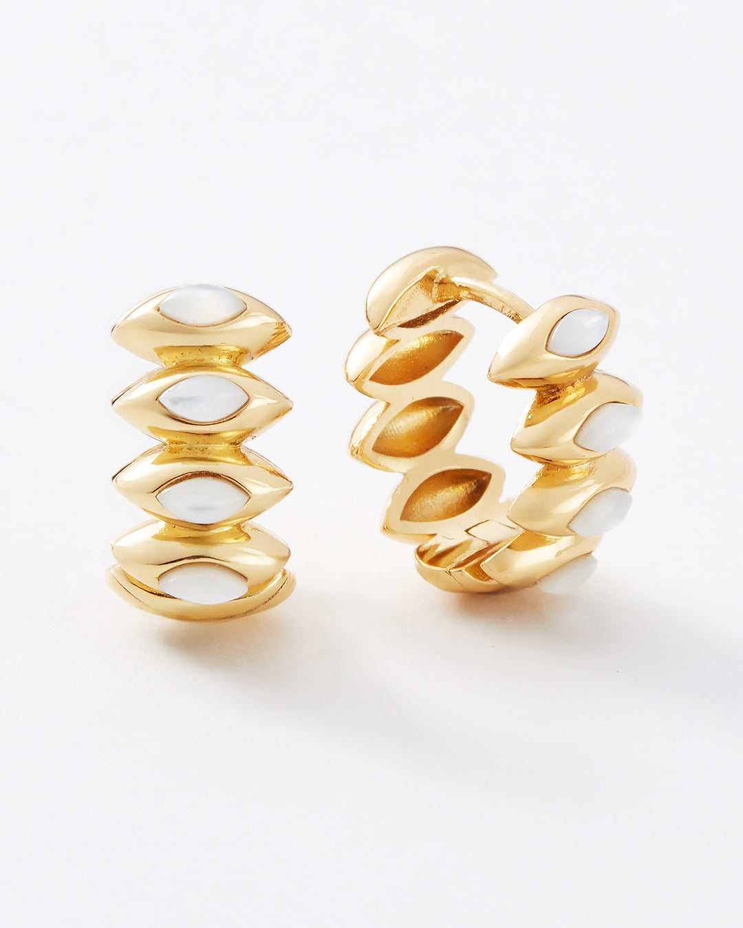 A pair of gold huggie hoop earrings with stacked, rounded petal-like segments inlaid with white stone accents, shown on a clean white background.