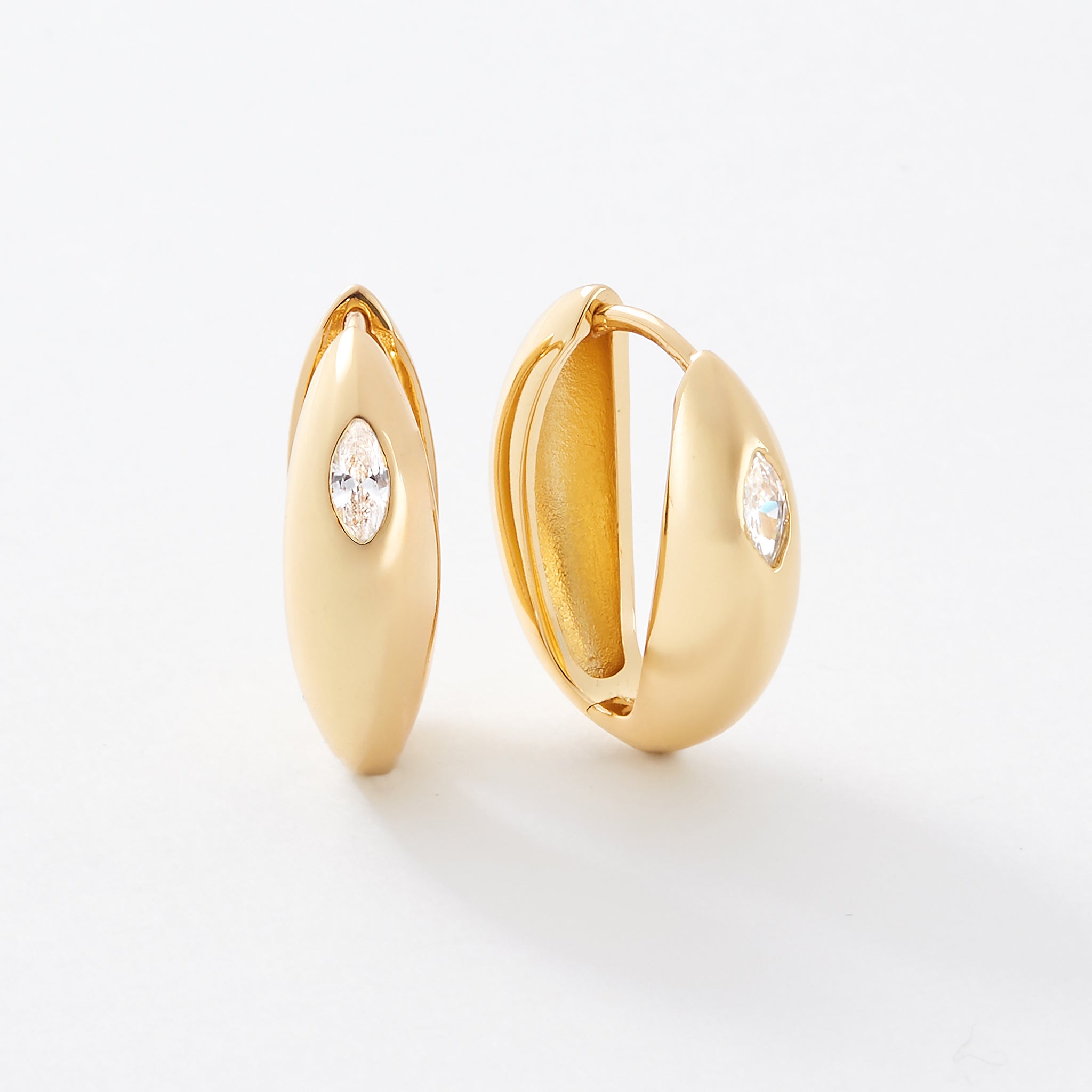 Gold hoop hinge earrings with white marquise shaped gemstones.
