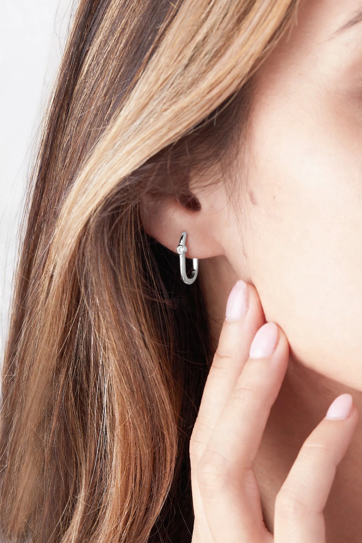 Midi reversible sterling silver hoop earring worn on a model, showing the white topaz side.