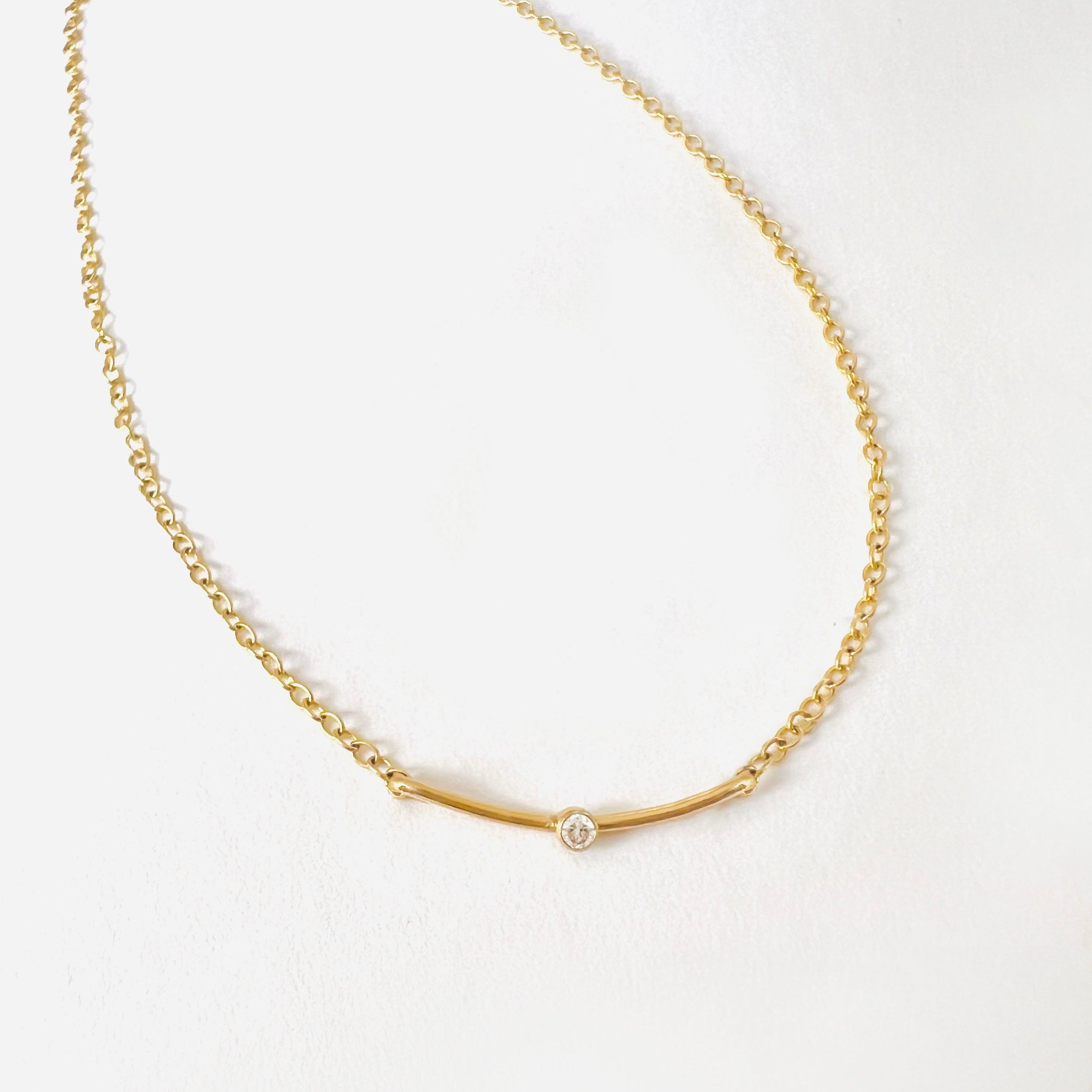 Tiny white topaz gemstone necklace. Curved bar style gold pendant.