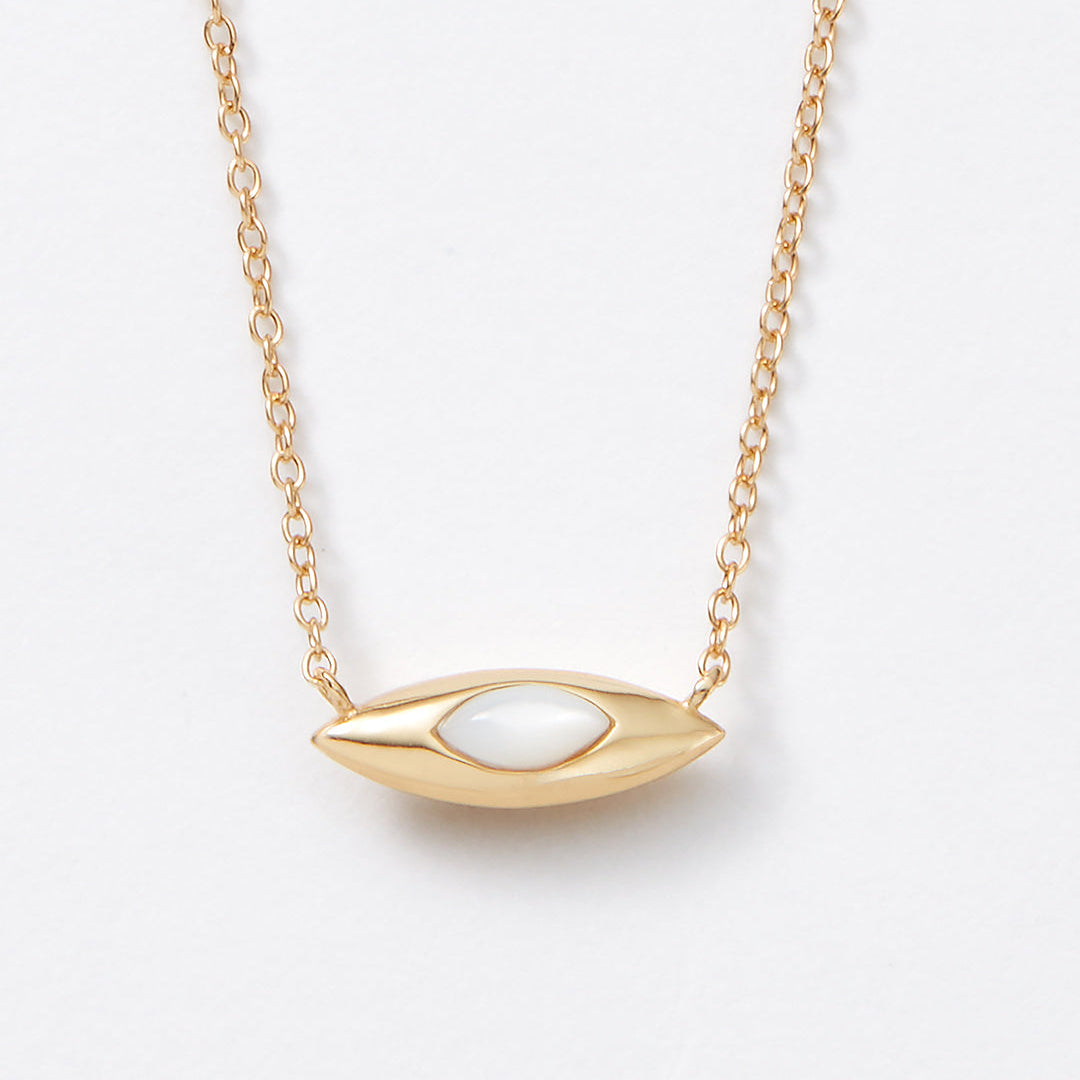 Gold necklace with a unique double sided pendant on a light gray background