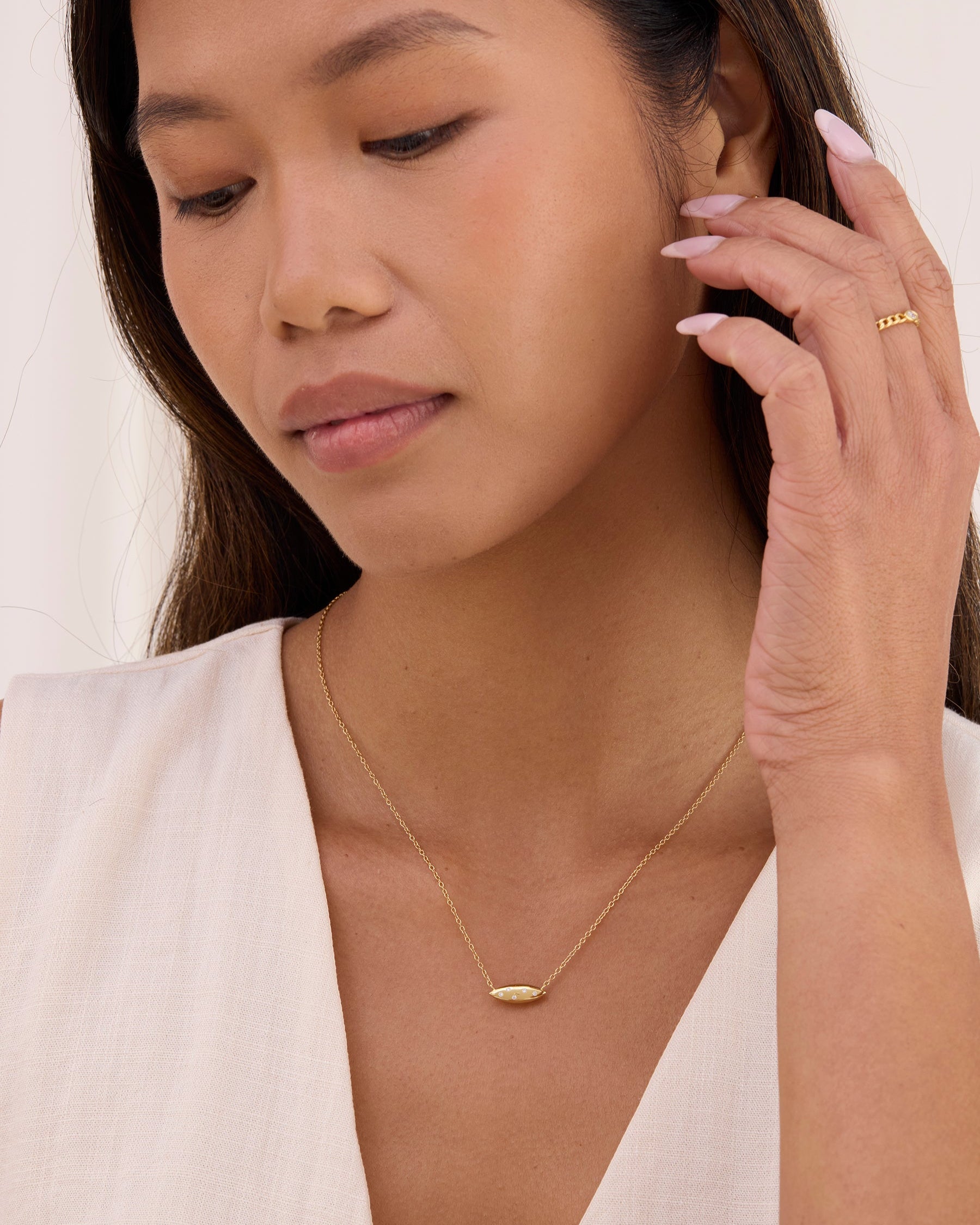 Womens gold necklace with petal shaped pendant with white topaz. Pendant is double sided.