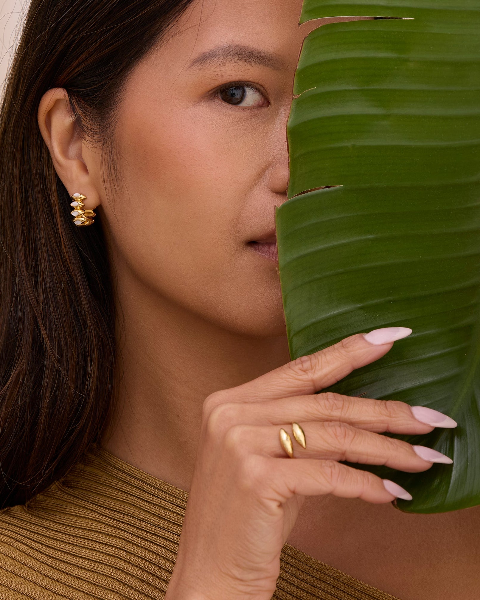 Women wearing gold open leaf ring on woman that makes a statement. Simple and modern sculptural shaped ring.