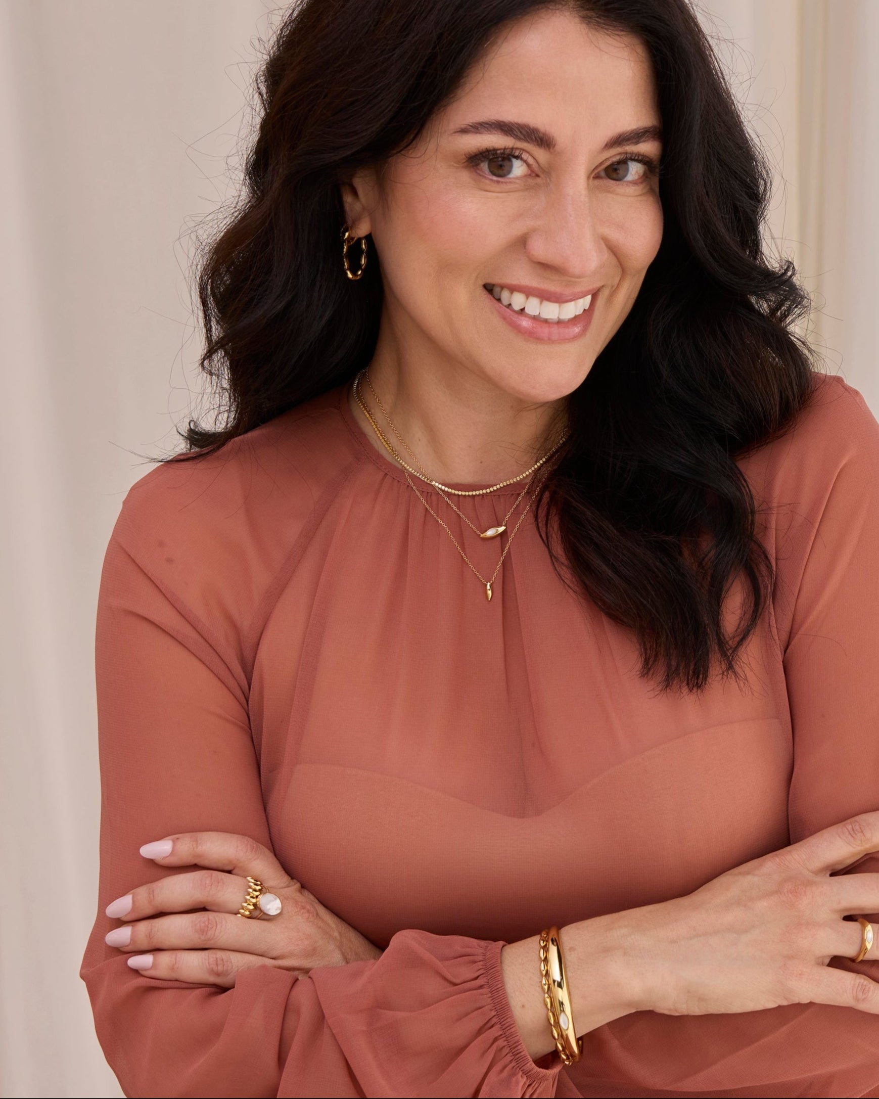 Women wearing gold necklaces, stacks of rings and bangles with natural gemstones.