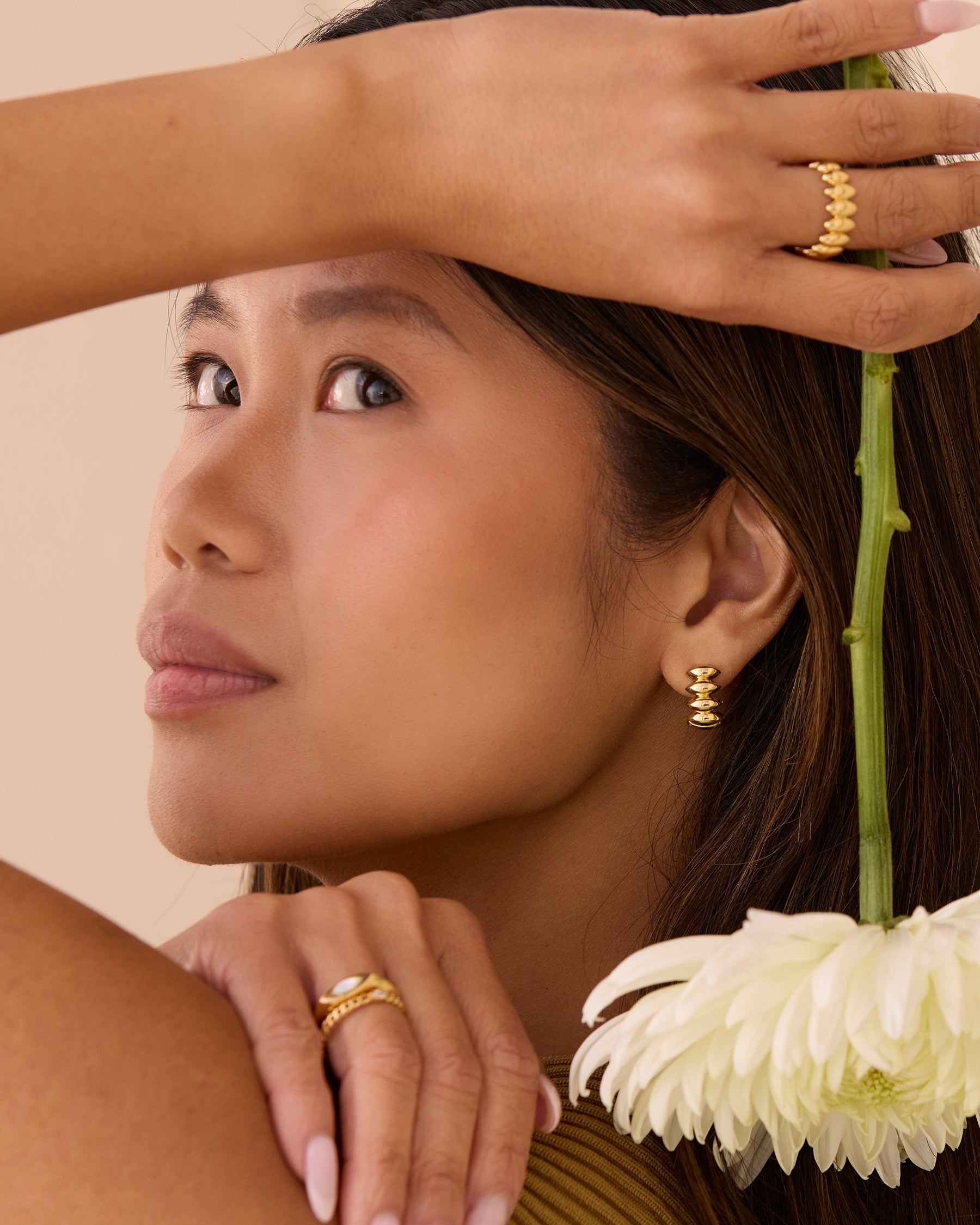 Woman with gold stacking rings and wide gold ring. Simple, dainty rings and a wide band ring.