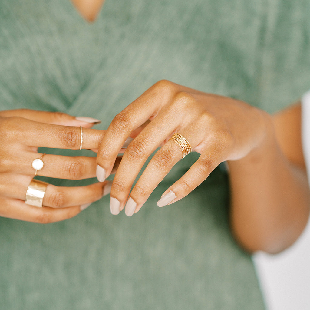 Thin gold hammered bands are very versatile. Style with other stackable rings. Shown here with pearl ring and white topaz ring. All recycled gold rings.