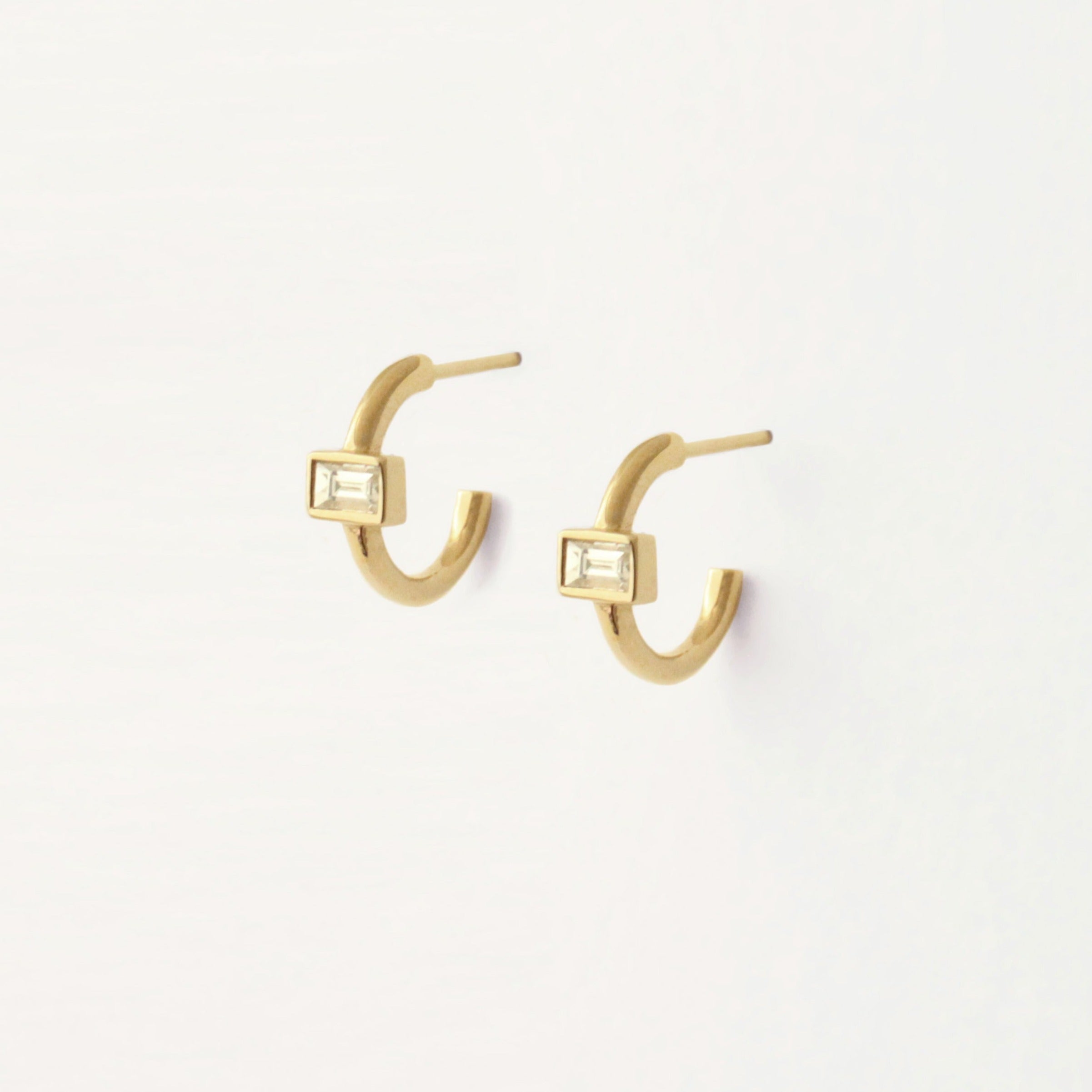 Baguette huggie hoops with baguette centered horizontally on the 14k yelllow gold hoop. It's elegant and simple. An elevated everyday piece of jewelry.