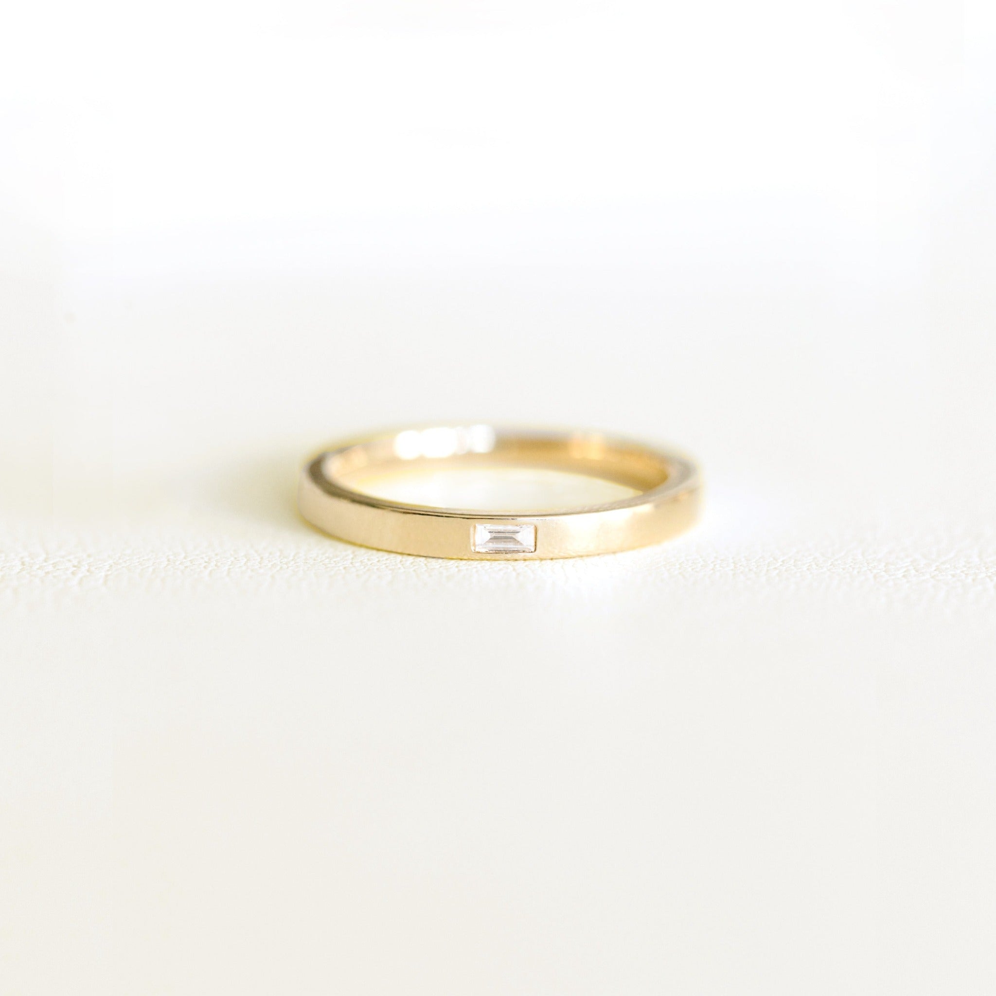 Recycled 14k yellow solid gold ring with a baguette diamond. The band is wide, is stackable and comfortable. A modern simple gold ring design.