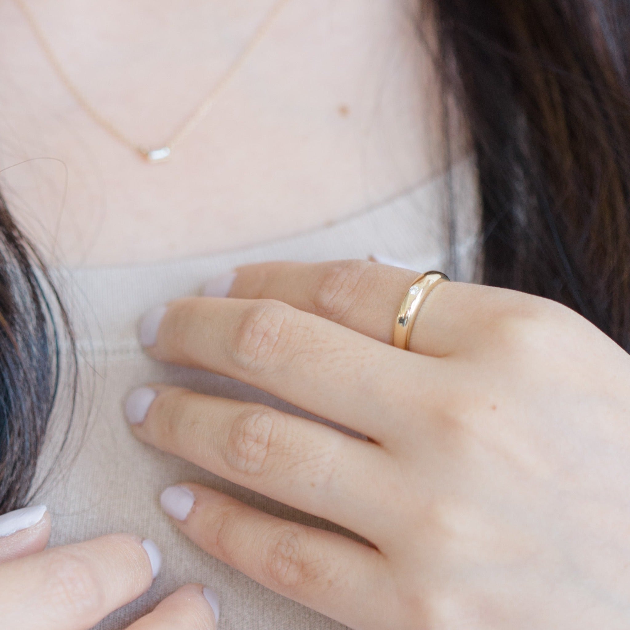 Model is wearing gold diamond dome ring on its own. The ring's surface is a shiny polished finish.